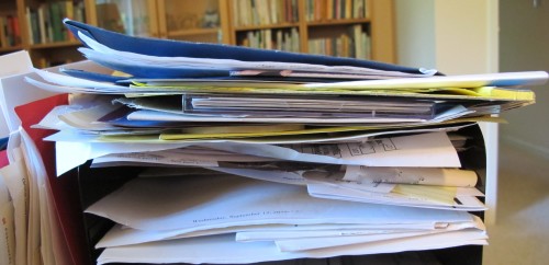 Papers stacked in a home office inbox -- like a spam-riddled email in-blox. Photo by Barbara Newhall