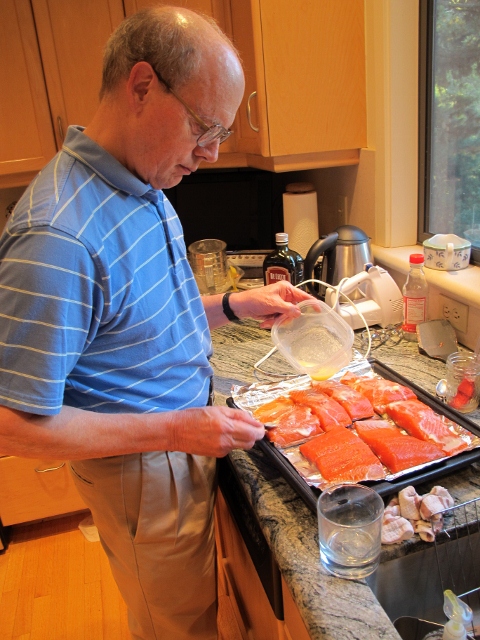 Jon pouring butter on salmon on kitchen counter. Photo by Barbara Falconer Newhall