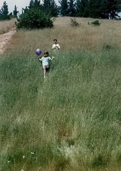 Peter and Christina playing in a field with a balloon. 