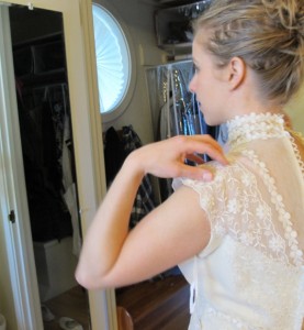 Bride looks at herself in mirror wearing vintage gown. Photo by BF Newhall