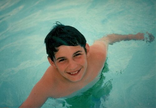 eight-year-old boy smiling up from a swimming pool. photo by bf newhall
