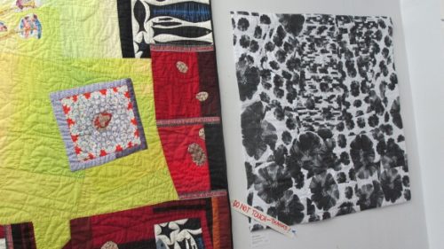 A colorful assymetrical art quilt and a quilt with black fleurs du mal against a white background by Donna Duguay of Berkeley, CA. Photo by BF Newhall