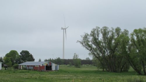 A wind turbine in the Lake Winds Energy Project towers above a painted shed in Mason County, Michigan. Photo by BF Newhall