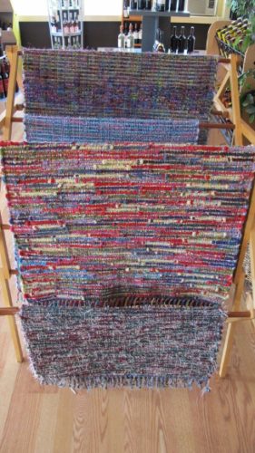 A rack in Gull Landing store showing several multicolored rugs hand woven by Mary Helen Blohm. Photo by BF Newhall