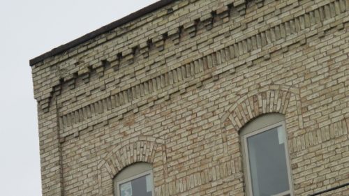 Detail of the gustafson building, pentwater, michigan showing the intricate yellow brick work and the tall narrow 19th century windows. Photo by bf newhall