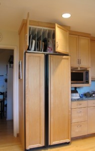 A cupboard over a refrigerator with vertical slats for storing platters, trays and cookie sheets. Photo by BF Newhall