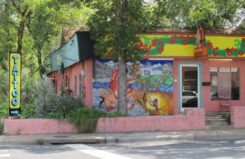 colorful mural decorates the front of a store in Austin TX selling books, T-shirts and CDs. And tattoos. Photo by BF Newhall