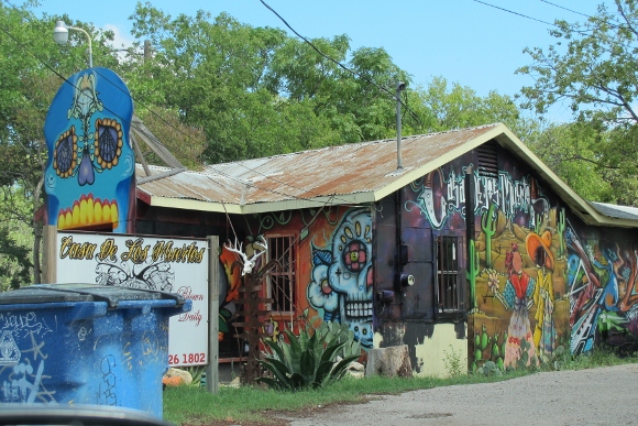 Graffiti and murals cover the Casa de los Muertos tatoo and head shop blows glass pipes on site. Austin TX. Photo by BF Newhall