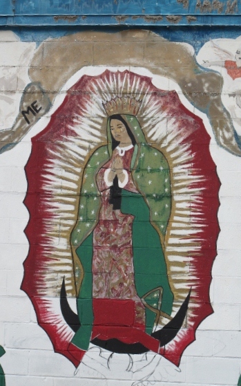 Detail of a grren, white and red mural depicting the Virgin of Guadalupe on the outer wall of a laundramat in East Austin , TX. Photo by BF Newhall.