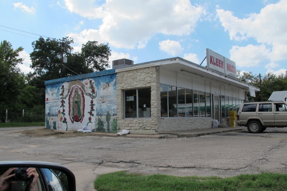 An elaborate mural of the Virgin of Guadalupe is painted on the side of the Kleen Wash laundramat in East Austin, TX. the mural includes an image of an airplane crashing into the Twin Towers on 9/11. Photo by BF Newhall.