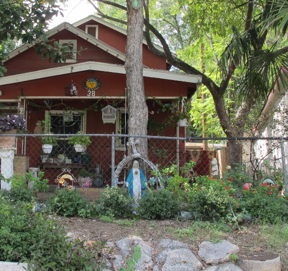 A small statue of the Virgin Mary stands amidst flowers and trees in an Austin, TX, front yard. Photo by BF Newhall