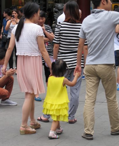 A couple walks hand-in-hand with their toddler in the streets of Shanghai. Photo by BF Newhall