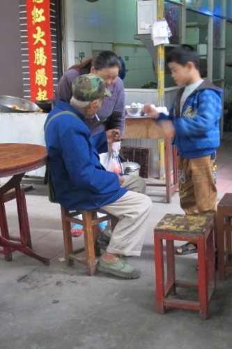 Grandparents in outdoor shop tend their grandchild in China. Photo by BF Newhal