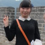 A chinese girl in navy sweater and white collar gives the peace sign to foreigners on the GReat Wall. Photo by BF Newhall