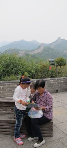 At the Great Wall of China an older woman tourist entertains two small children. Photo by BF Newhall