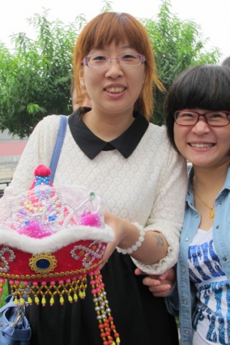 Two teenaged Chinese girls getting their picture taken in Beijing. One has dyed her hair orange.