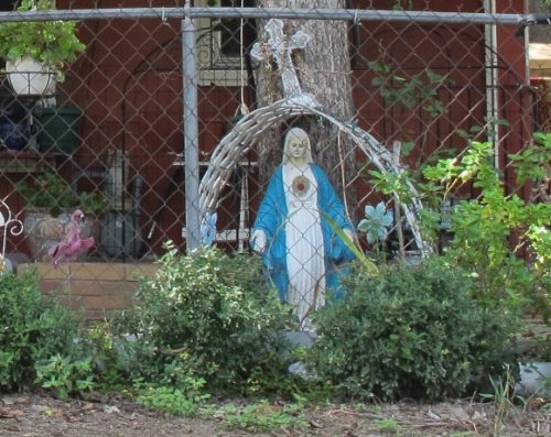 A statue of the Virgin Mary in blue and white clothes and outstretched arms in a front yard in Austin, TX. Photo by BF Newhall