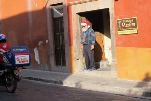 An man wearing a Santa Claus hat in a doorway in San Miguel de Allende just before Christmas. Photo by BF Newhall