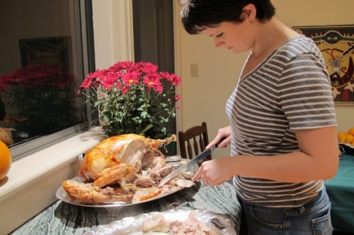 A young woman carves the Thanksgiving turkey in the kitchen. Photo by BF Newhall