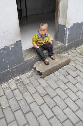 In Suchow, this little boy was set out on the doorstep of his house to pee, To expedite things, his pants were open at the crotch. I have preserved his dignity by retouching the photo to close up his fly. Photo by BF Newhall