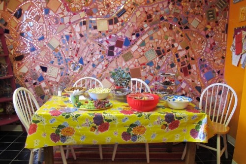 Food is served at Jingletown Art Studio on a table with flowered oilcloth tablecloth before a pink mosaic wall. Photo by BF Newhall