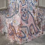 detail of pastel mosaic on facade of a building in Jingletown, Oakland, CA, showing body of dog wrapped around corner of building. Photo by BF Newhall