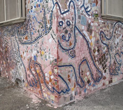 detail of pastel mosaic on facade of a building in Jingletown, Oakland, CA, showing body of dog wrapped around corner of building. Photo by BF Newhall