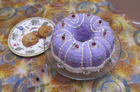 A lavendar mosaic bundt cake on a table alongside a plate of cookies at the Institute of Mosaic Art, Berkeley, CA. Photo by BF Newhall