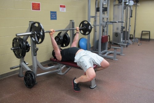 A 33-year-old man wearing white shorts bench presses at the gym Photo by BF Newhall