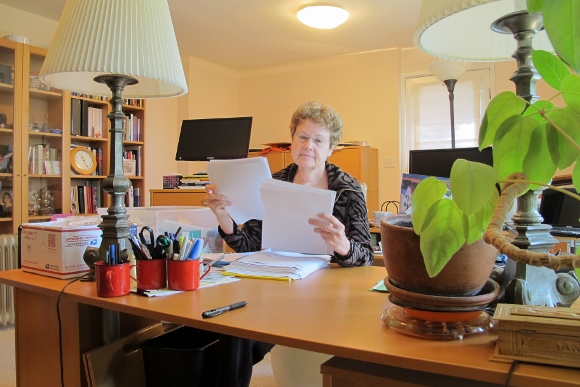 Barbara Falconer Newhall in her San Francisco Bay Area writing room with desk and bookcases editing the paper print-out of her book manuscript, "Wrestling with God." Photo by Barbara Newhall