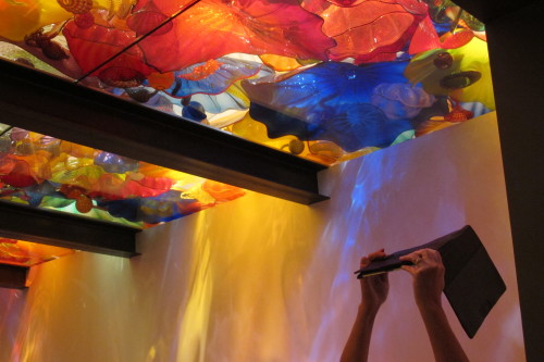 A museum-goer uses an etablet to photograph the colorful ceiling of Dale Chihuly's Sealfe Room at the Chihuly Garden and Glass museum in Seattle. Photo by Barbara Newhall