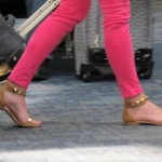 A woman wearing gold sandals and tight pink leggings pulls a carry-on at SFO airport. Photo by Barbara Newhall