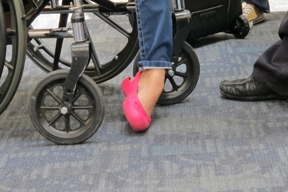 A woman at SFO with only one foot wears stylish bright pink shoe and ankle length jeans. Photo by Barbara Newhall