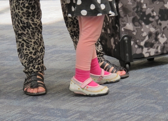 Mother and daughter wait for airplane at SFO. The girl wears pink socks, her mother wears camouflage pants. PHoto by Barbara Newhall
