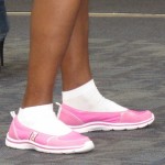 A young woman at SFO wears bright pink slip-on sneakers with bright white socks. Photo by Barbara Newhall