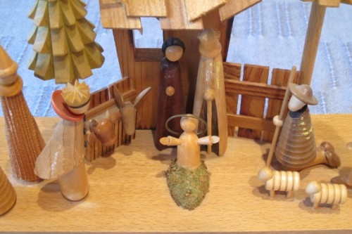 A Christmas nativity scene of hand-carved wood with open armed baby Jesus. Photo by Barbara Newhall