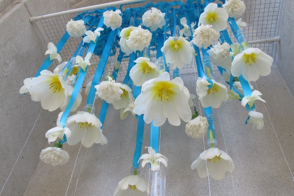 White tulips suspended upside down with blue ribboms part of a design for Mountain View Cemetery Exhibition by Merritt College Floral Design Department. Titled "Puddle Jumping." Photo by Barbara Newhall