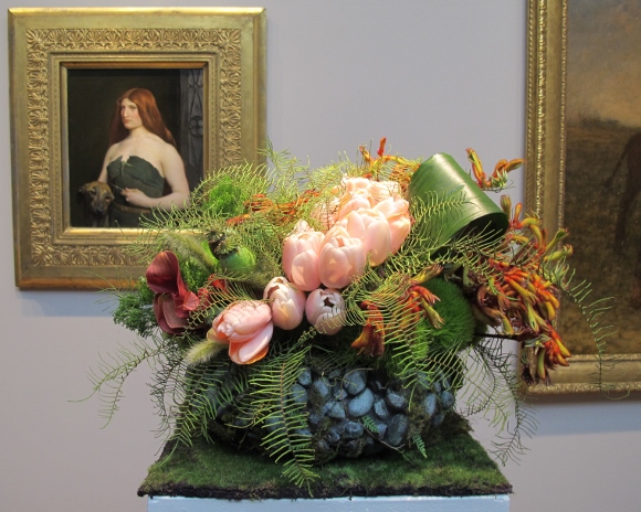 Floral design at the FAMSA Bouquets to Art exhibition 2015 by Andrea Frenkel of Ukiah, CA. Lily and Mint. the design complements George DF Brush's 1890 painting "A Celtic Huntress."