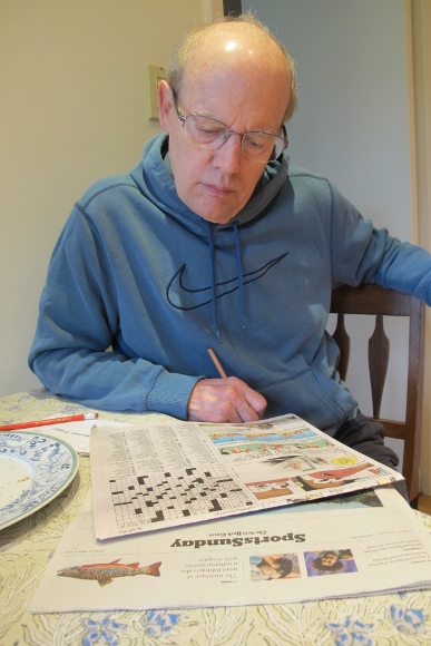 Retired and enjoying himself, Jon Newhall works on the New York Times Sunday crossword puzzle as it appears in the San Francisco Chronicle. Photo by Barbara Newhall