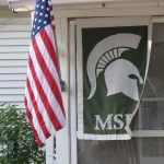 American flag flies next to a Michigan State University Trojans banner. Lots of Michigan State fans in Pentwater. Photo by Barbara Newhall