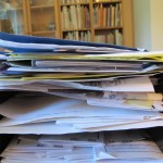 an inbox on a desk filled with stacked papers. Not as jammed as a spam-riddled email inbox. Photo by Barbara Newhall