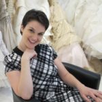 A bride wearing a plaid dress sits among frothy wedding dresses at Le Marriage, LA. Wedding dress shopping. Photo by Barbara Newhall