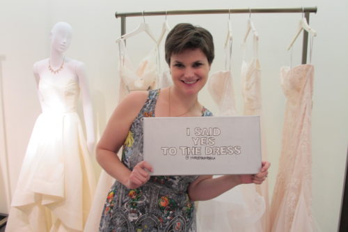 A young bride celebrates choosing a wedding dress with a "I said yes to the dress" sign.. Photo by Barbara Newhall