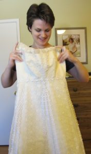 Christina Newhall holds up her mother's wedding dress for size. It's too small. Yes to the dress. Photo by Barbara Newhall