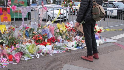 A mourner brings red carnations to a memorial on International Avenue near the scene of the Oakland Ghost Ship fire. Photo by Barbara Newhall