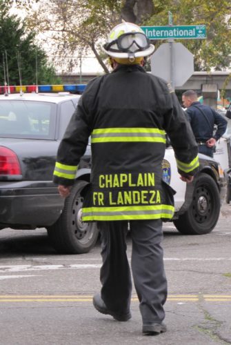 Chaplain Fr. Jayson Landeza, Catholic priest, at the scene of the Oakland Ghost Ship fire that killed 36 mostly young people, artists, musicians, LGBTQ folks. A few days after the fire, it was cordoned off as a "crime scene." Photo by Barbara Newhall
