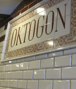Up close shot of subway tiles in Budapest metro station with grimy grout and Oktogon station sign. Photo by Barbara Newhall