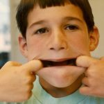 A 7-year-old boy makes a face by stretching his mouth wide. Photo by Barbara Newhall