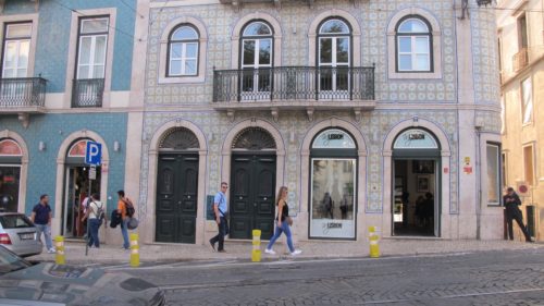 A woman wearing white sneakers strolls past a tiled store front in the Baixa district of Lisbon. Photo by Barbara Newhall