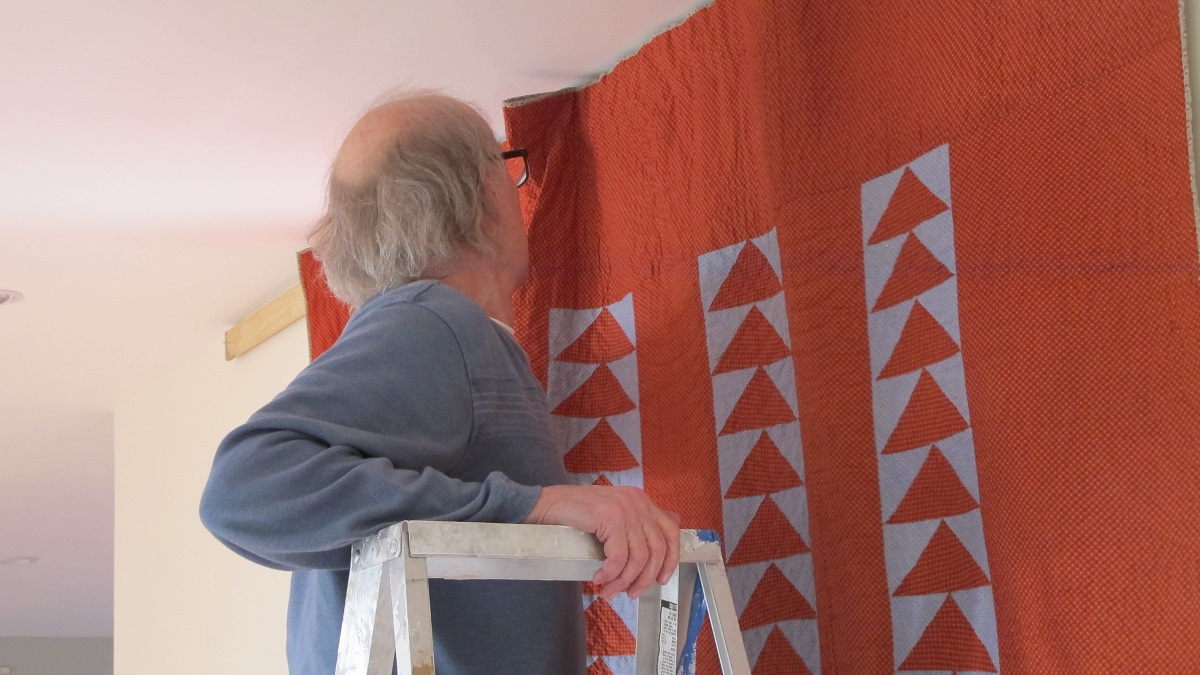 how-to-hang-a-quilt man-hanging-a-quilt